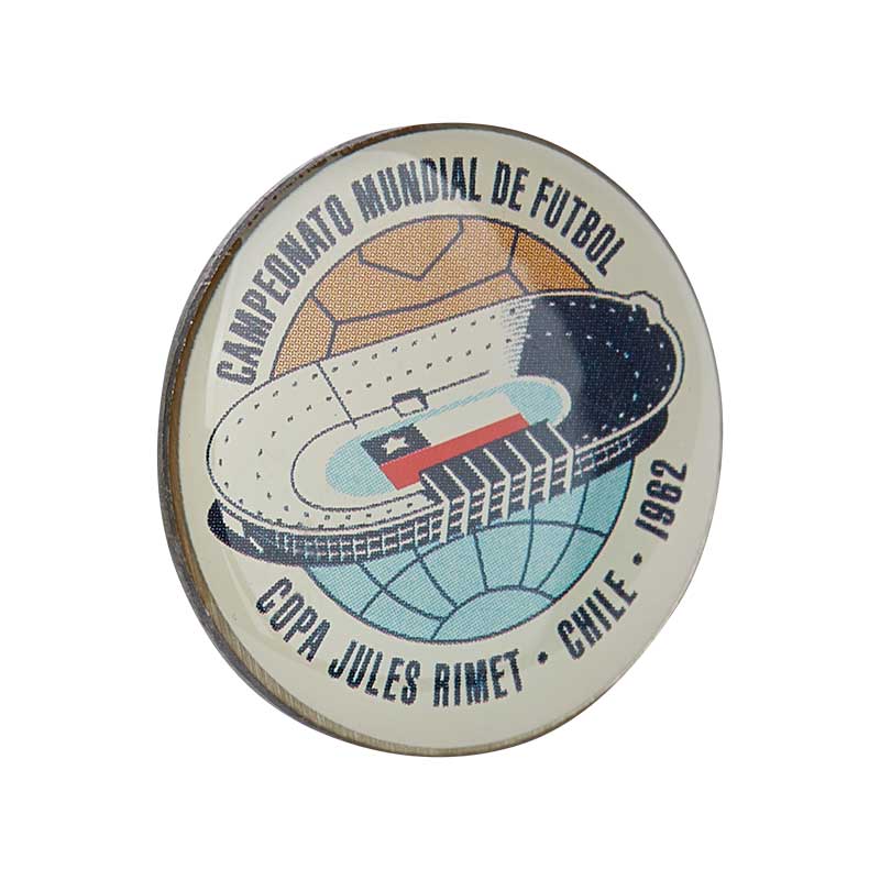Round pin in white & blue with a stadium in the middle & the Chilean flag, representing the FIFA World Cup celebration in 1962 in Chile.