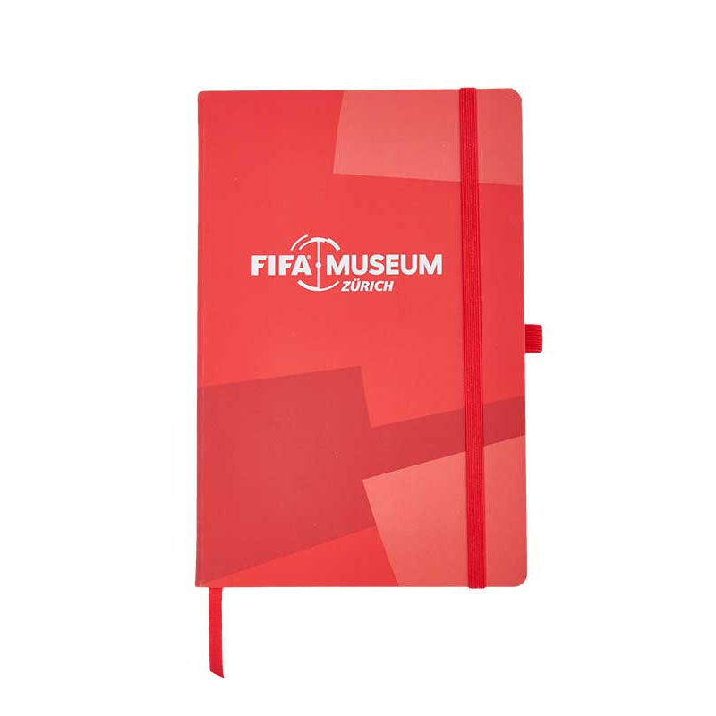 An A5 notebook in red with an elastic closure loop and 96 pages, with the logo Zürich FIFA Museum in the center.