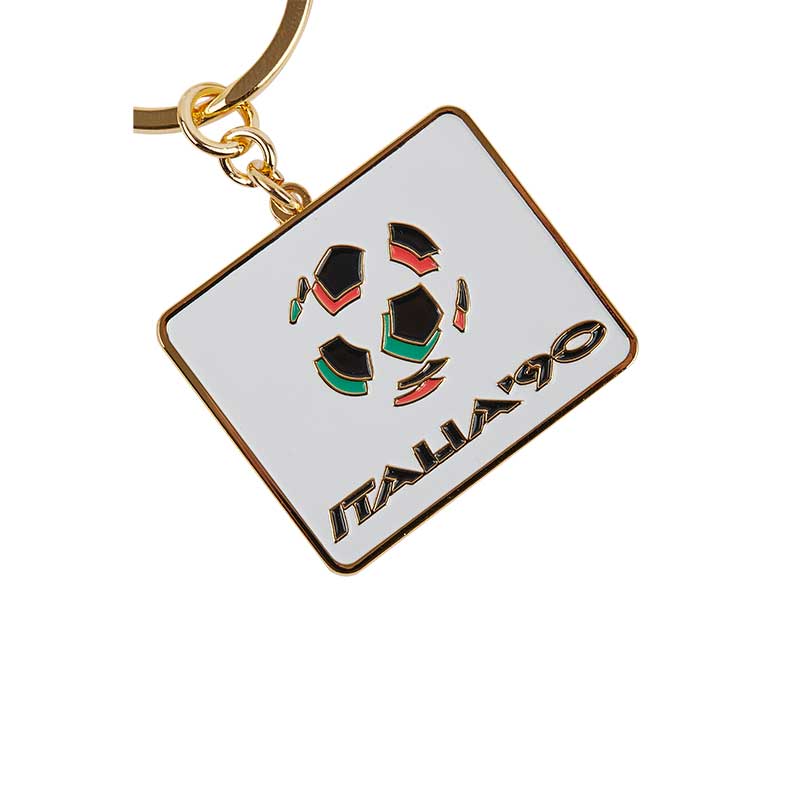 White keyring with rounded corners, a football in red, black, and green colors in the center, commemorating the FWC in Italy in 1990.